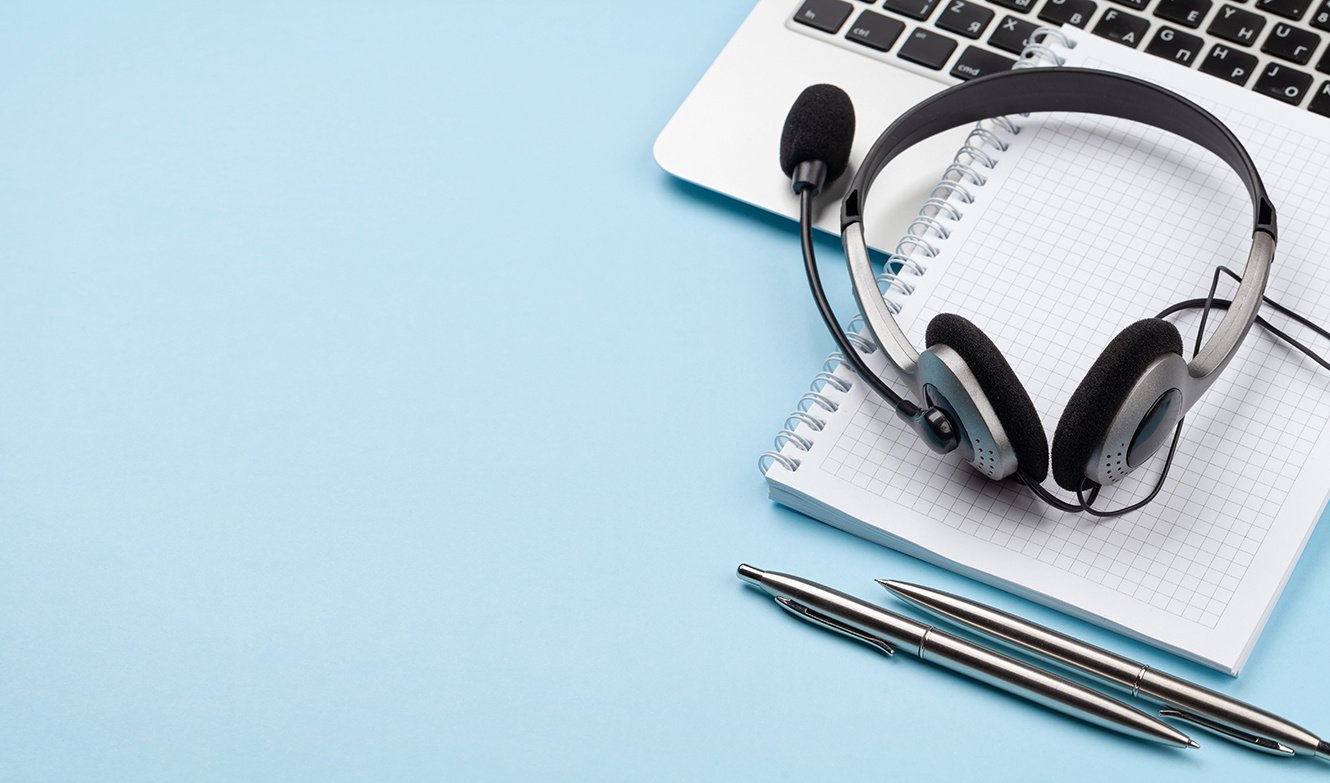 Høretelefoner og notesblok klar til webinar fra Xact