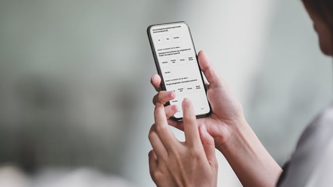 Kvinde holder mobiltelefon oppe, hvor hun besvarer spørgeskema