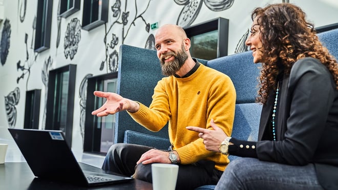 Lederevaluering: To kolleger diskuterer lederudvikling foran en bærbar computer.