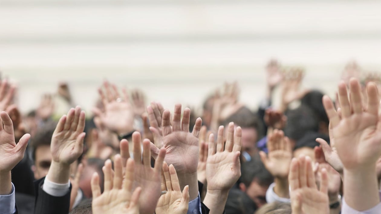 Billede af mange hænder rakt op, der illustrerer borgernes deltagelse i kommunen.