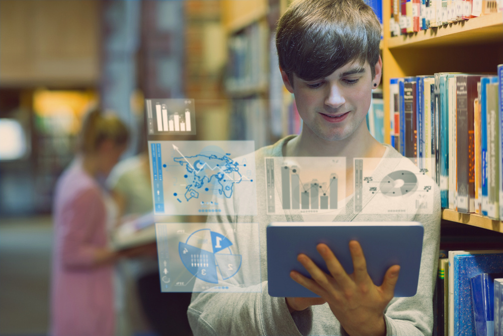 Young man studying on his digital tablet computer in a library